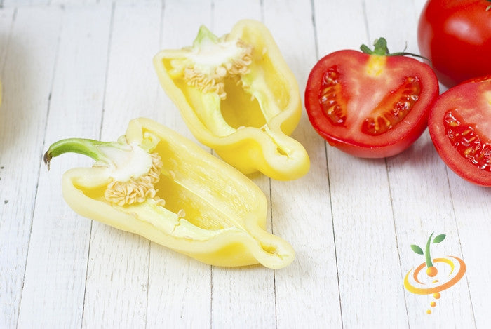Yellow jalapeño pepper cut open with red tomatoes on a wooden surface
